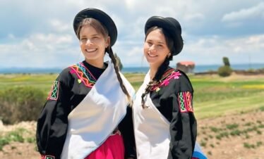 Visitors in Luquina Chico traditional clothing smiling by Lake Titicaca in Puno, Peru