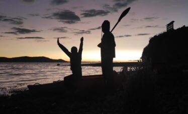 Golden dawn illuminating tranquil waters of Lake Titicaca with Luquina Chico in Puno, Peru