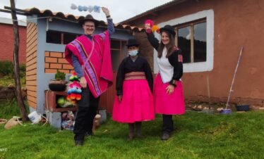 Visitors in colorful Aymara clothing sharing farewell with host family in Luquina Chico by Lake Titicaca Puno Peru