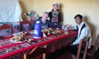 Travelers enjoying traditional breakfast with local family in Luquina Chico by Lake Titicaca Puno Peru
