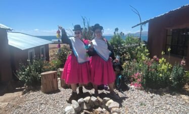 Travelers in colorful Aymara clothing sharing a moment in Luquina Chico guesthouse courtyard by Lake Titicaca Puno Peru