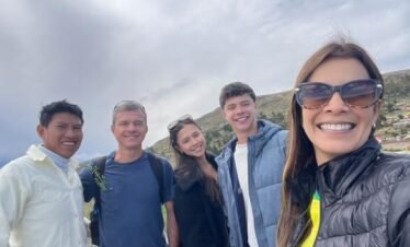 Local host taking joyful selfie with travelers in Luquina Chico by Lake Titicaca, Puno, Peru