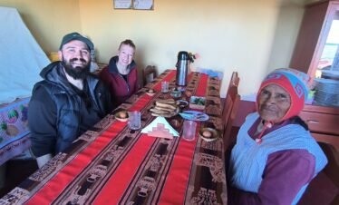 Local family sharing traditional breakfast with visitors in Luquina Chico by Lake Titicaca, Puno, Peru