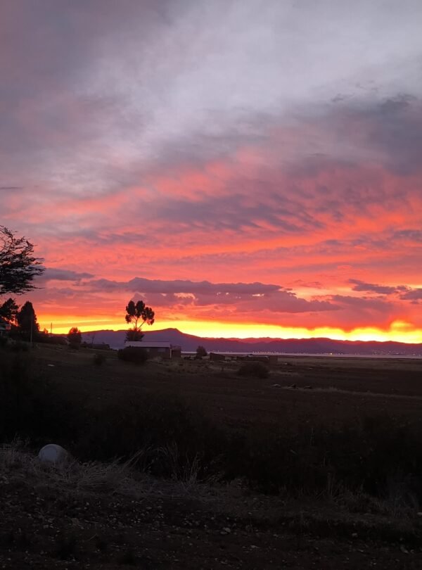 Evening colors reflecting on Lake Titicaca as sun sets behind Luquina Chico in Puno, Peru
