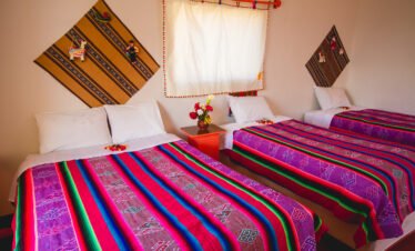 Brightly decorated beds with traditional Andean textiles inside guest rooms of Luquina Chico by Lake Titicaca Puno Peru